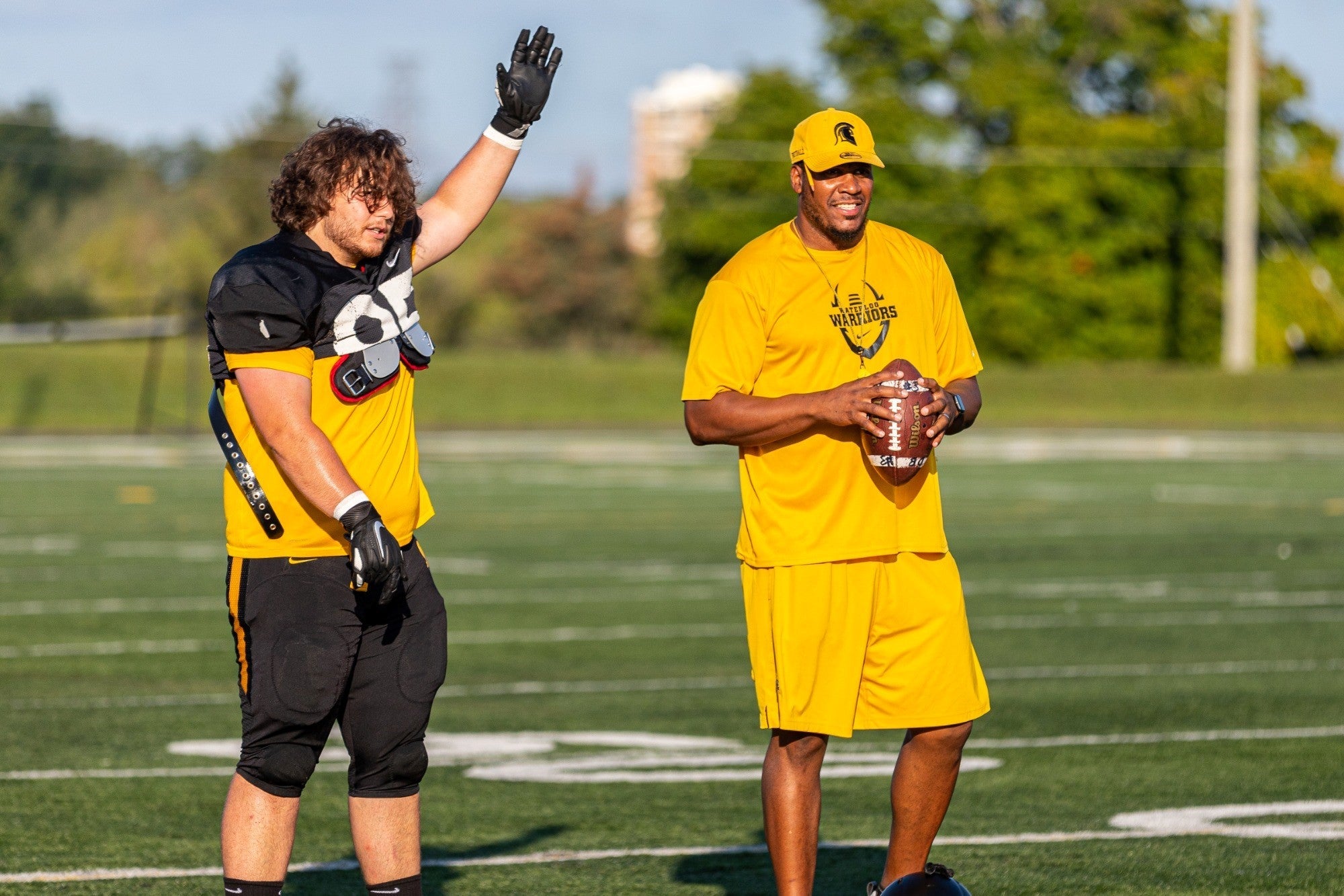 Coach Darrell Adams with a Warriors football player on the field.