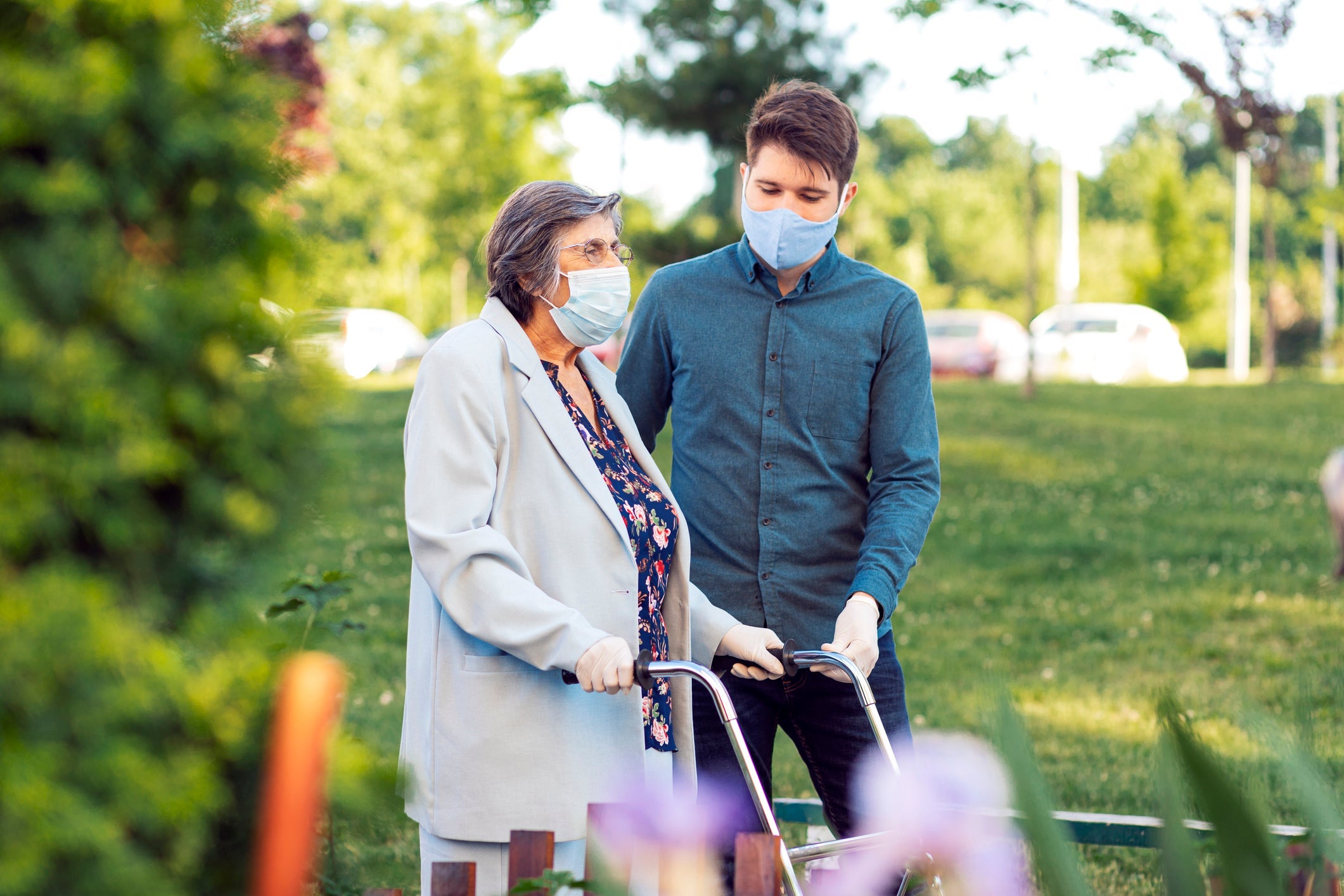 A person helps a woman using a walker.