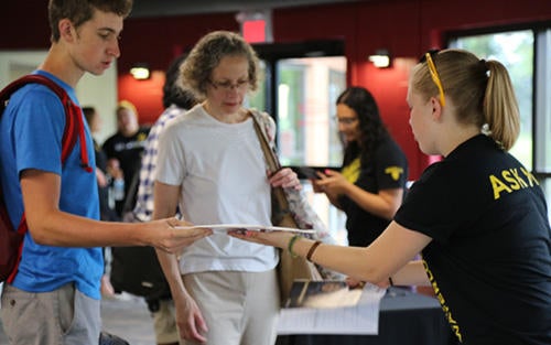 a staff volunteer helping a new student and his parent