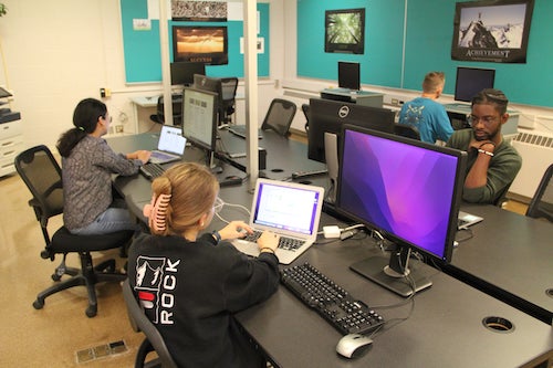Students in the ETIS workspace sit at computers.