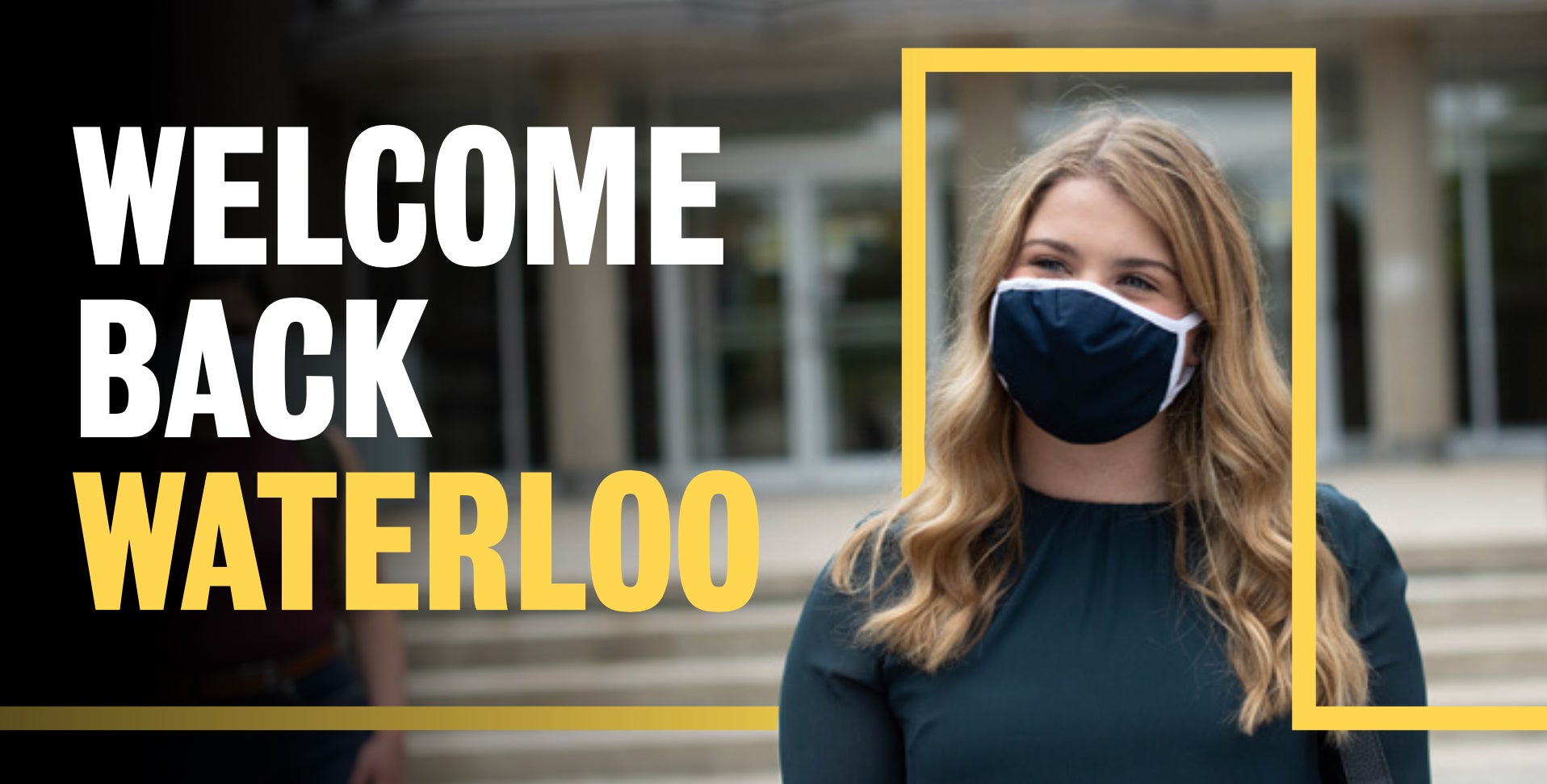 A young woman wears a mask outside a campus building.