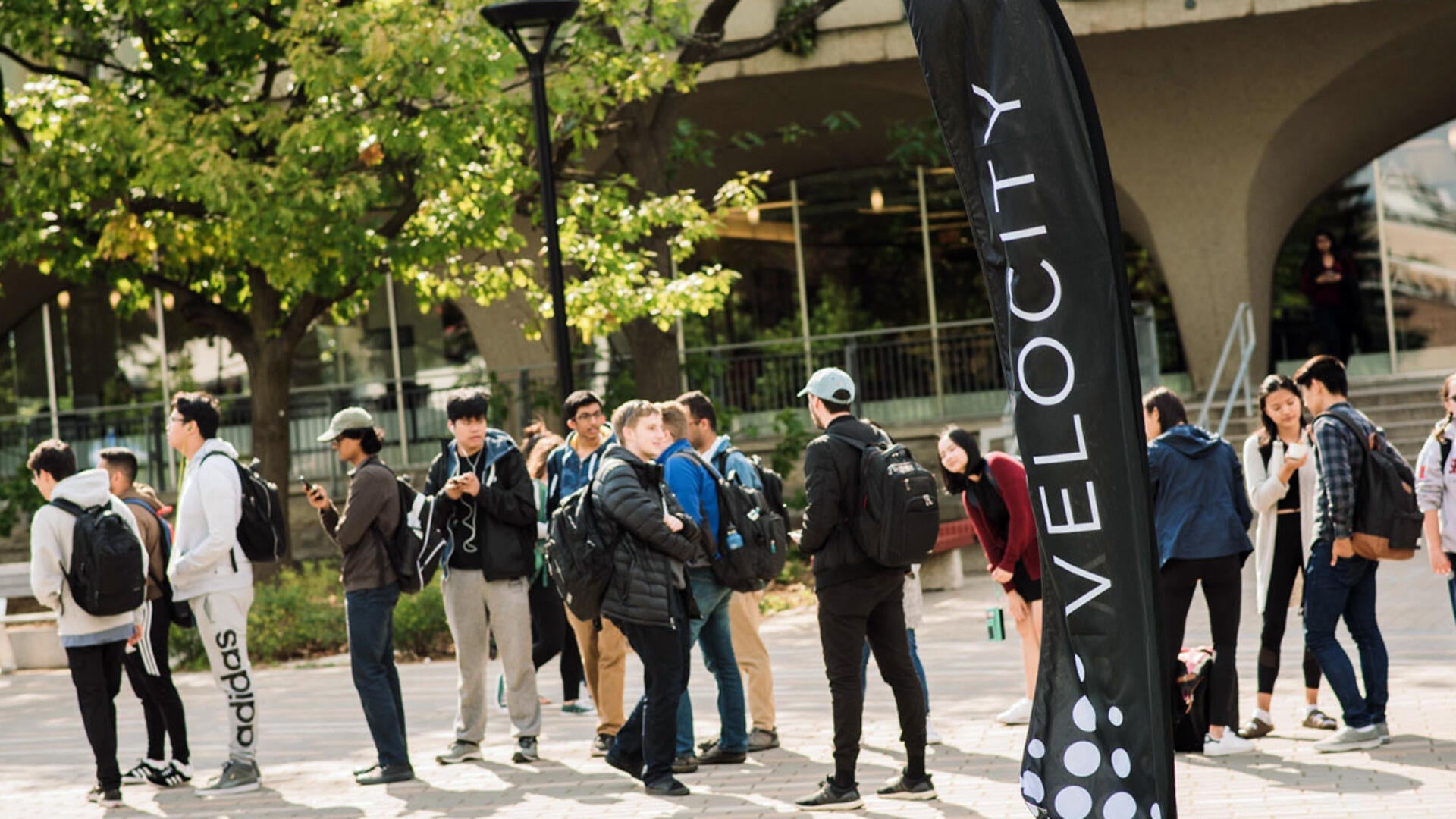 Students stand amid Velocity banners in the arts quad.