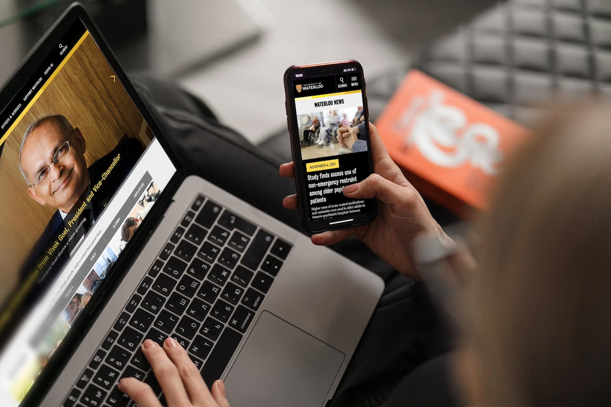 A person uses a website and a smartphone with UW web pages open on them.