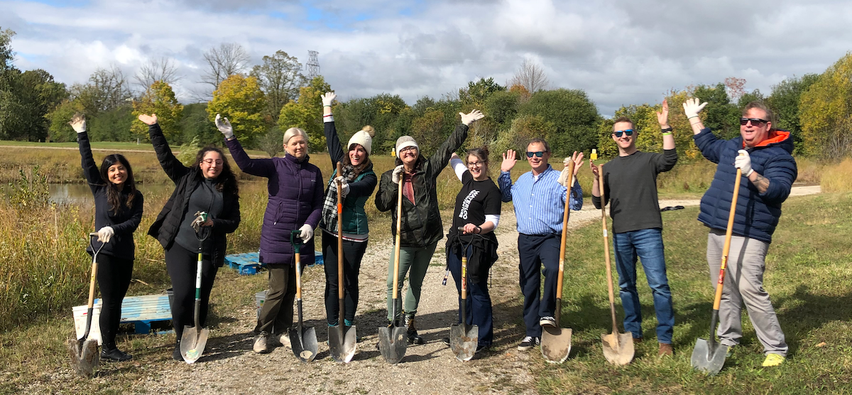 Volunteers wave and brandish their shovels on a campus path.