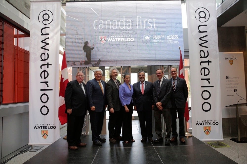 George Dixon, Mike Lazaridis, David Cory, Minister Kirsty Duncan, Feridun Hamdullahpur, Raymond Laflamme, and Brent Herbert-Copley stand in the Quantum-Nano Centre.