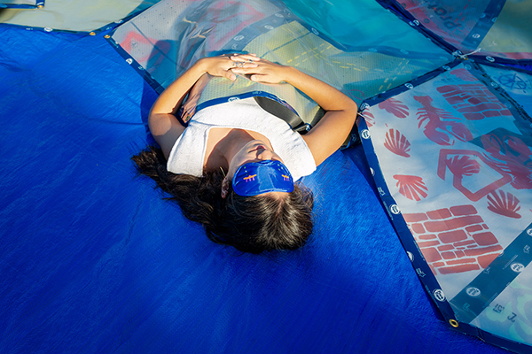 The artist wearing a mask reclines on the hexagonal quilt.