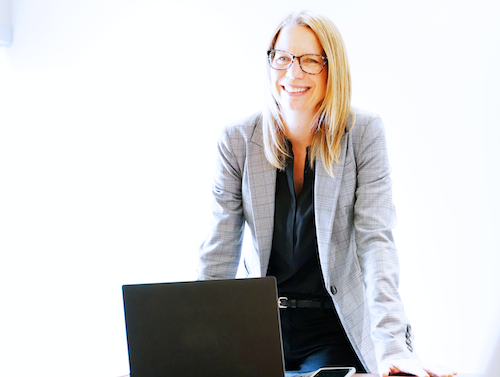 Jacinda Reitsma stands over a laptop and smartphone.