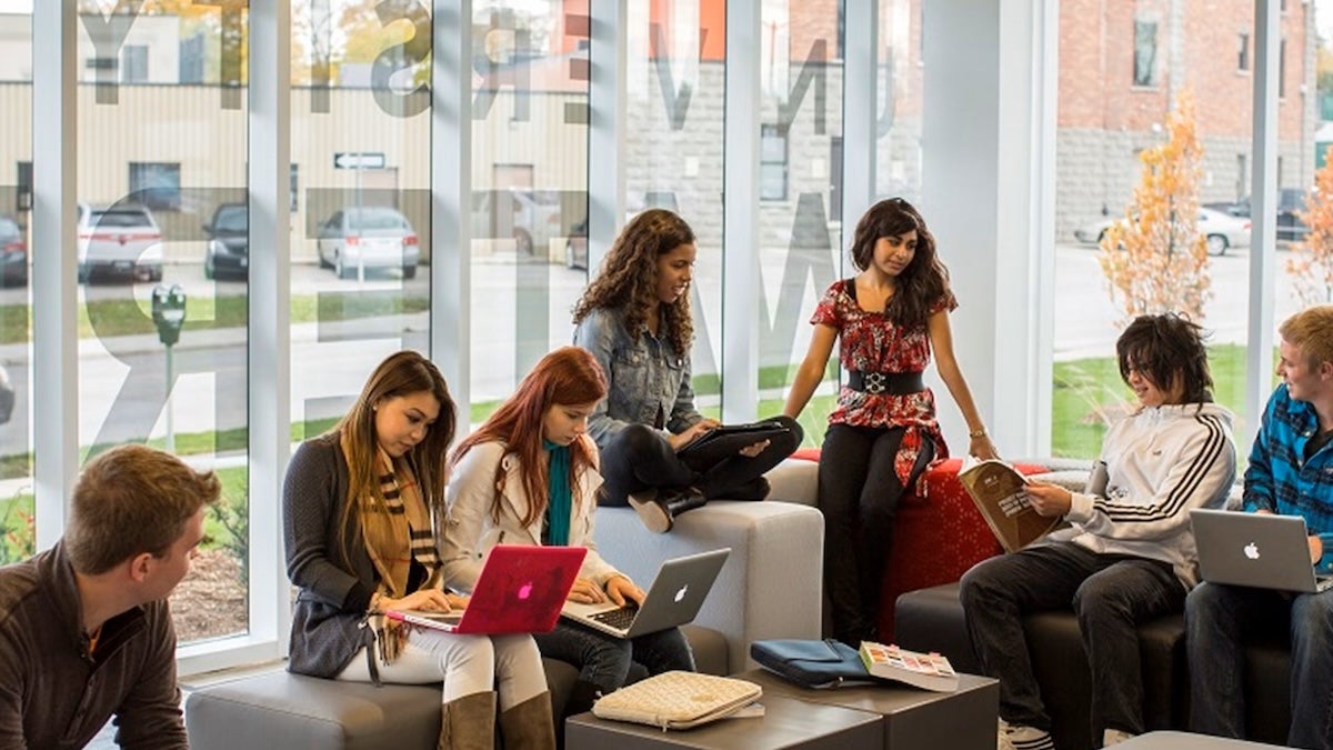 People sit and stand in a campus lounge space at Waterloo.