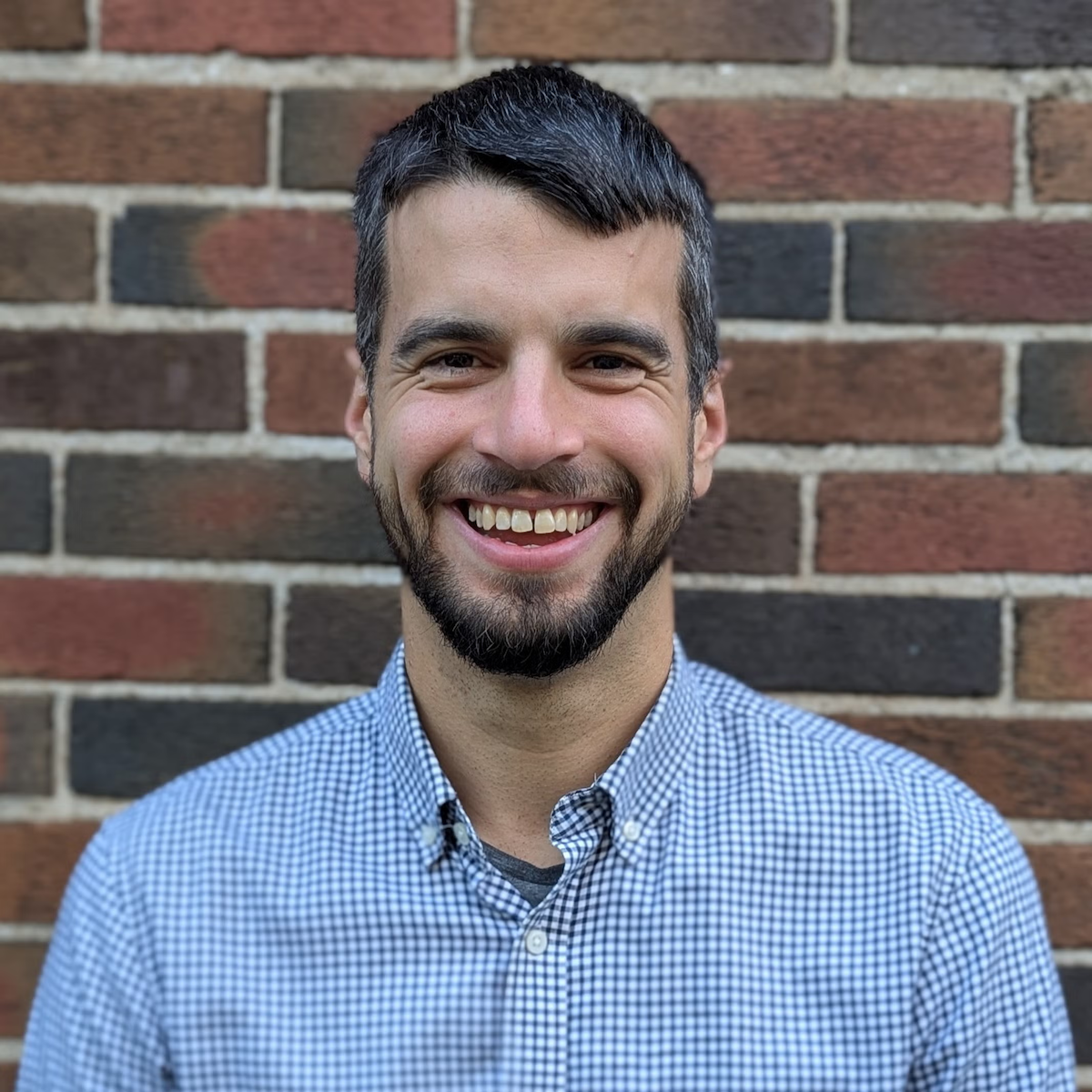 Chris Brnjas stands in front of a brick wall.