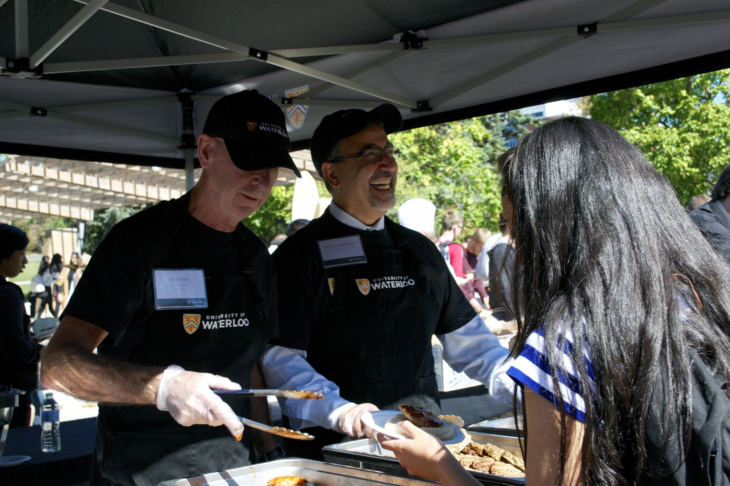 Ian Orchard and Feridun Hamdullahpur serve burgers.