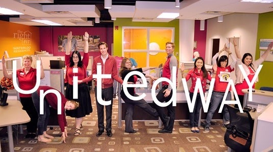 Housing volunteers wear red and pose with letters spelling out "United Way."