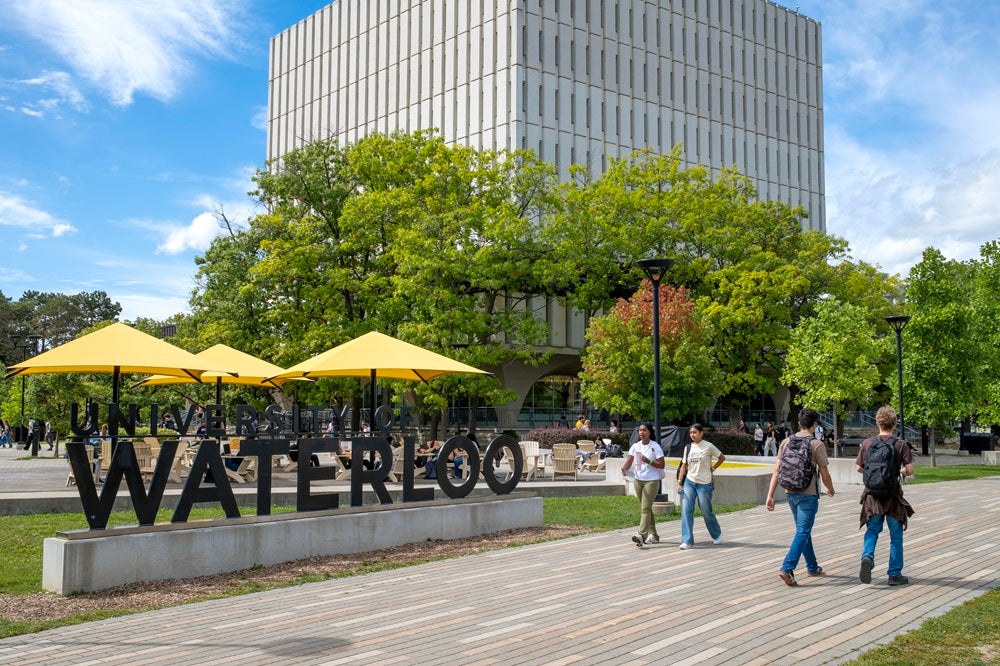 Campus sign with yellow umbrellas in the background.