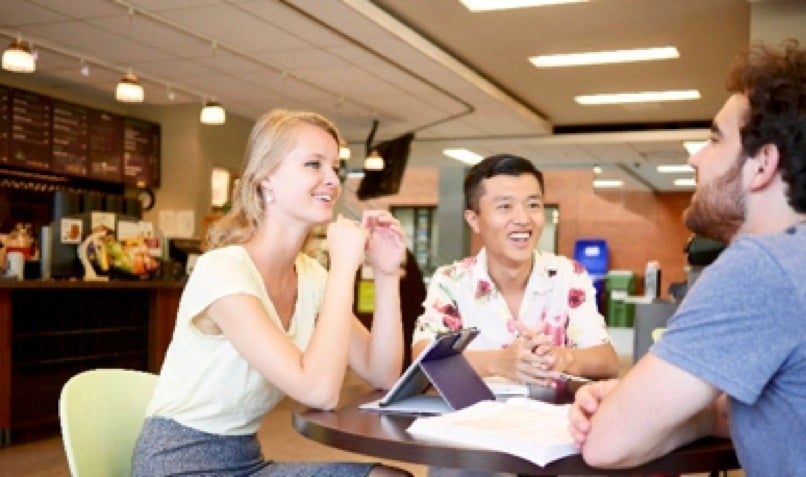 People converse at a table at the Go Abroad fair.