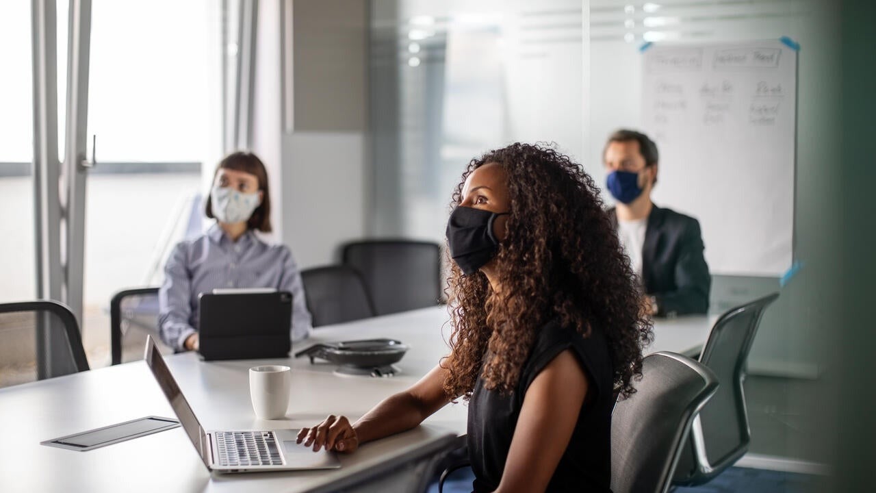 Three people in masks in a business meeting.