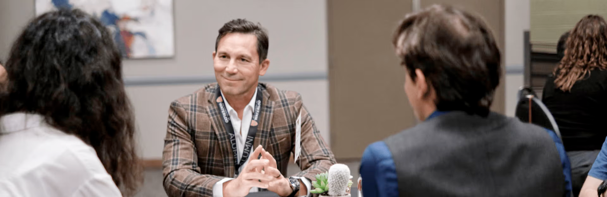 Three people sit at a table in conversation.