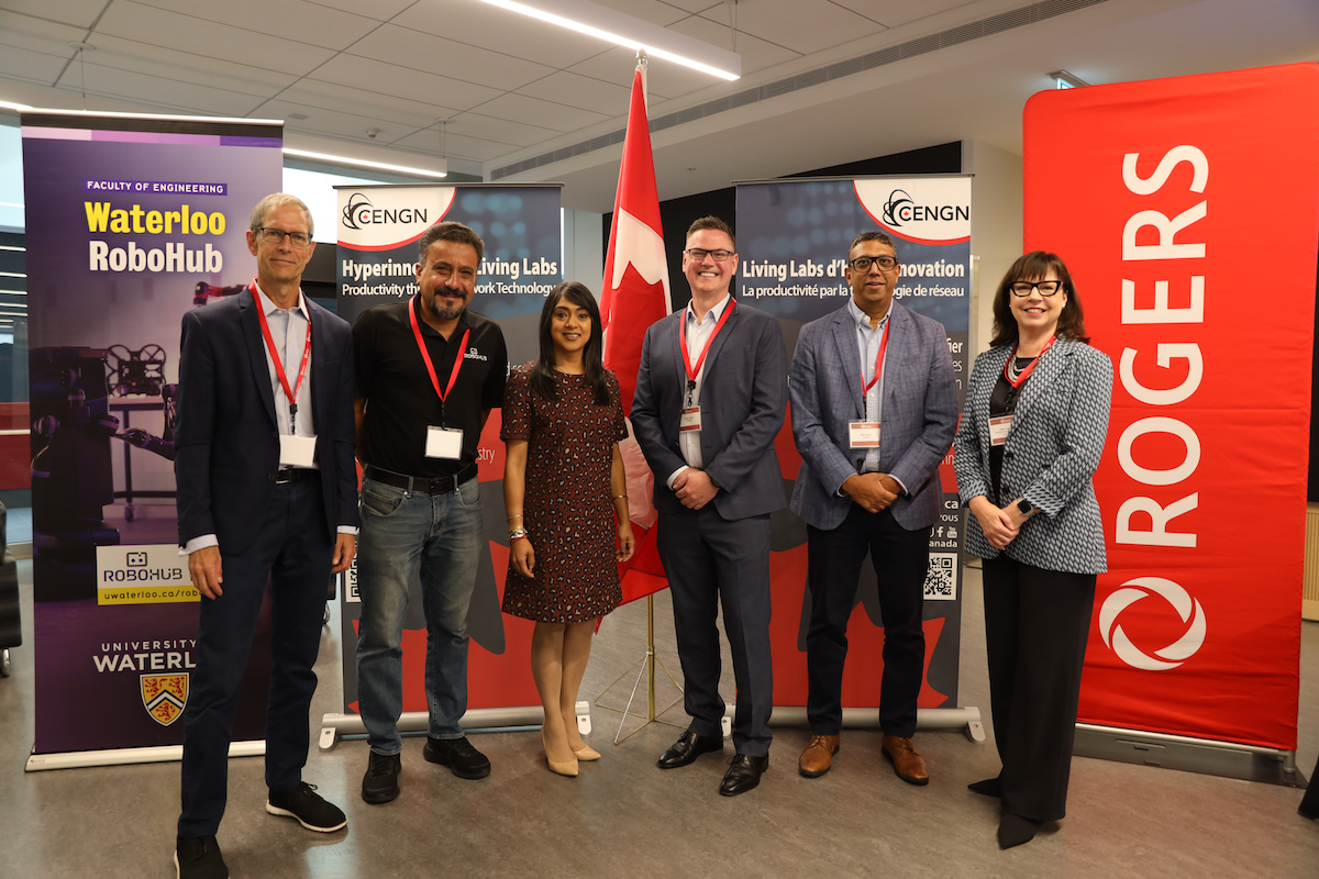 Tom Astle, William Malek, Bardish Chagger, Chris Joyce, Neel Dayal, and Pam Laycock stand next to a Robohub sign.