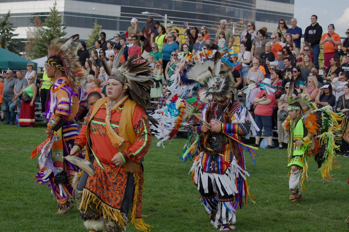 Dancers in traditional Indigenous regalia on the field at CIF Arena.
