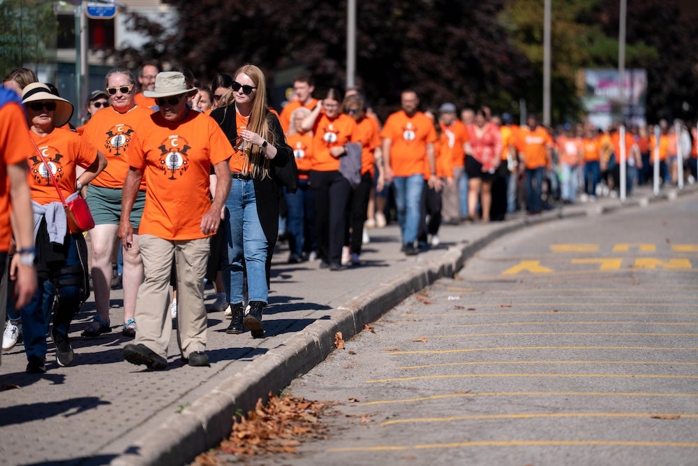 People wearing orange shirts walk around ring road.