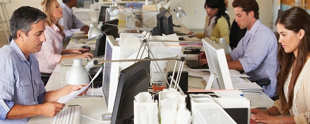 A busy office environment with employees seated at workstations.