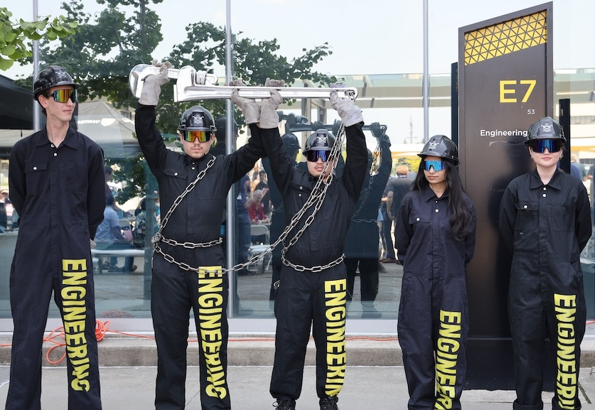 Five members of the Engineering Tool Guard in their sunglasses and black helmets, hoisting the Tool.