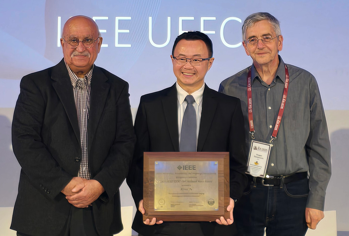 Dr. Alfred Yu stands next to two IEEE representatives as he receives the IEEE's 2025 Carl Hellmuth Hertz Award.
