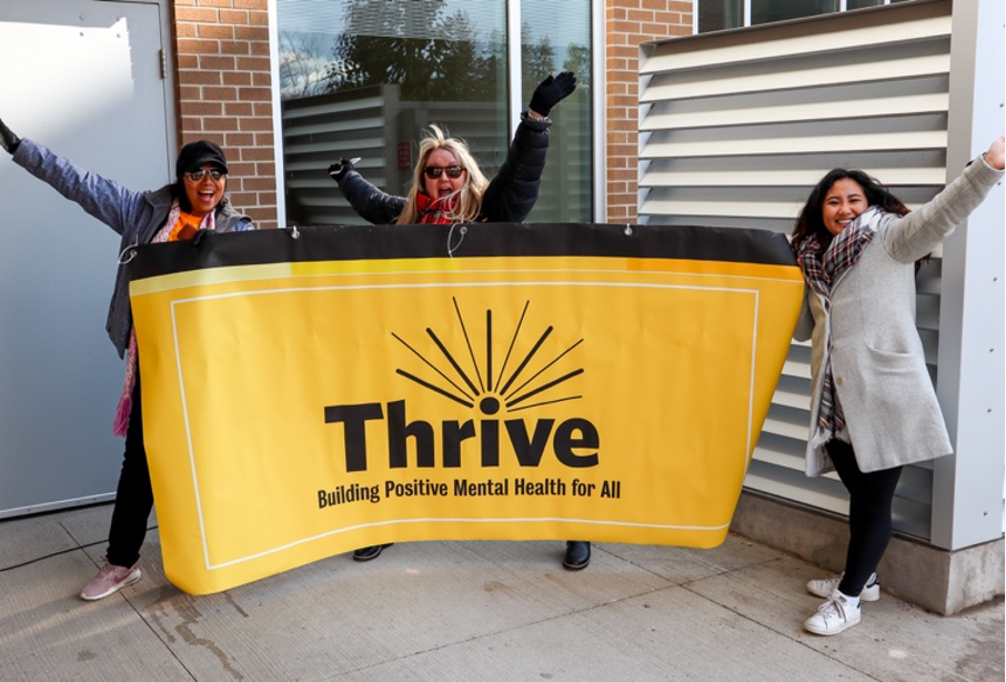 Volunteers hold up a yellow Thrive banner.