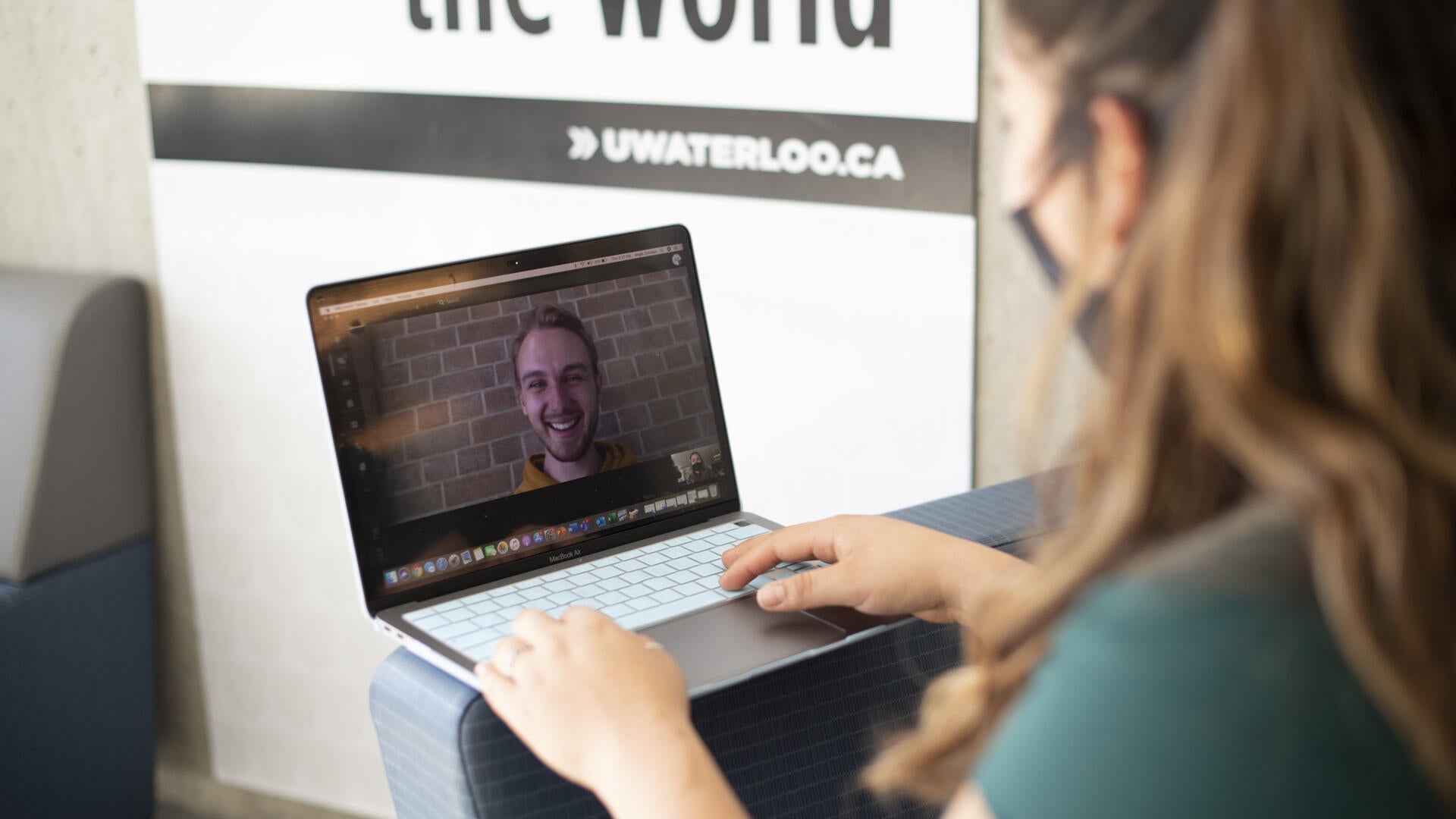 A masked woman has a video conference with a person via laptop.