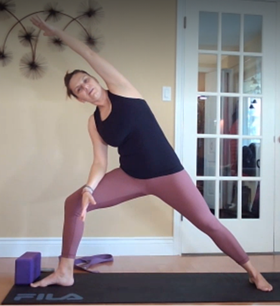 A woman does yoga on an exercise mat.