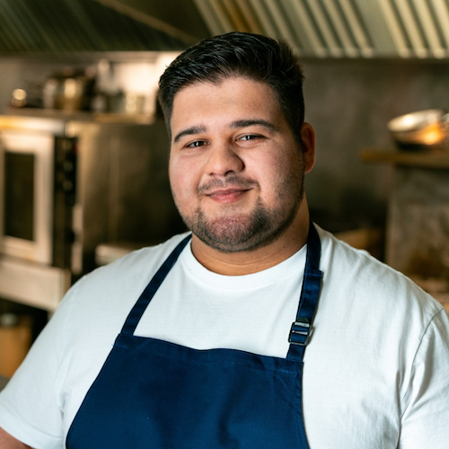 Teddy, a United Way campaign support recipient, wearing an apron in a kitchen.