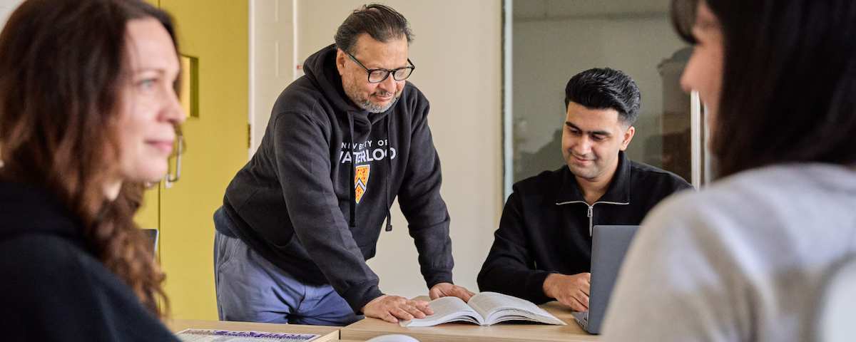 Supervisor helping student using textbook on table