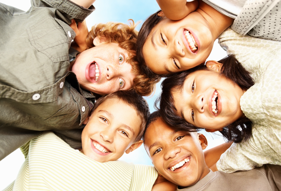 Five children in a circle smiling and looking down at camera