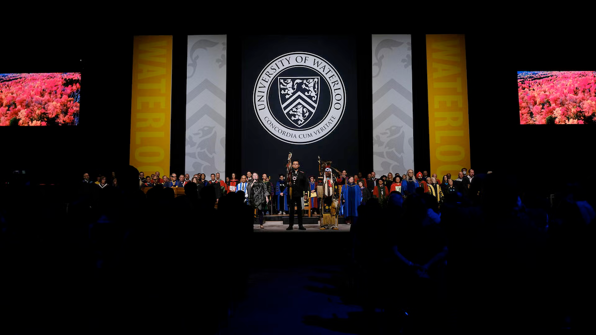 Participants stand on the Convocation stage.