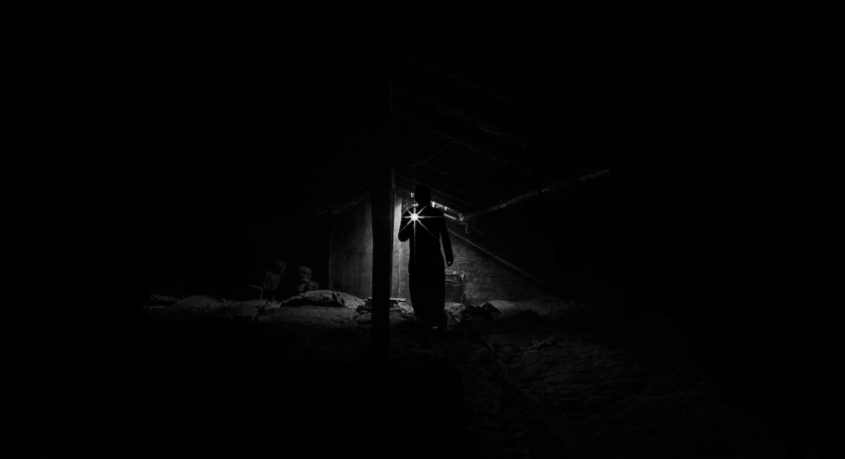 A person holds a flashlight in a darkened area.