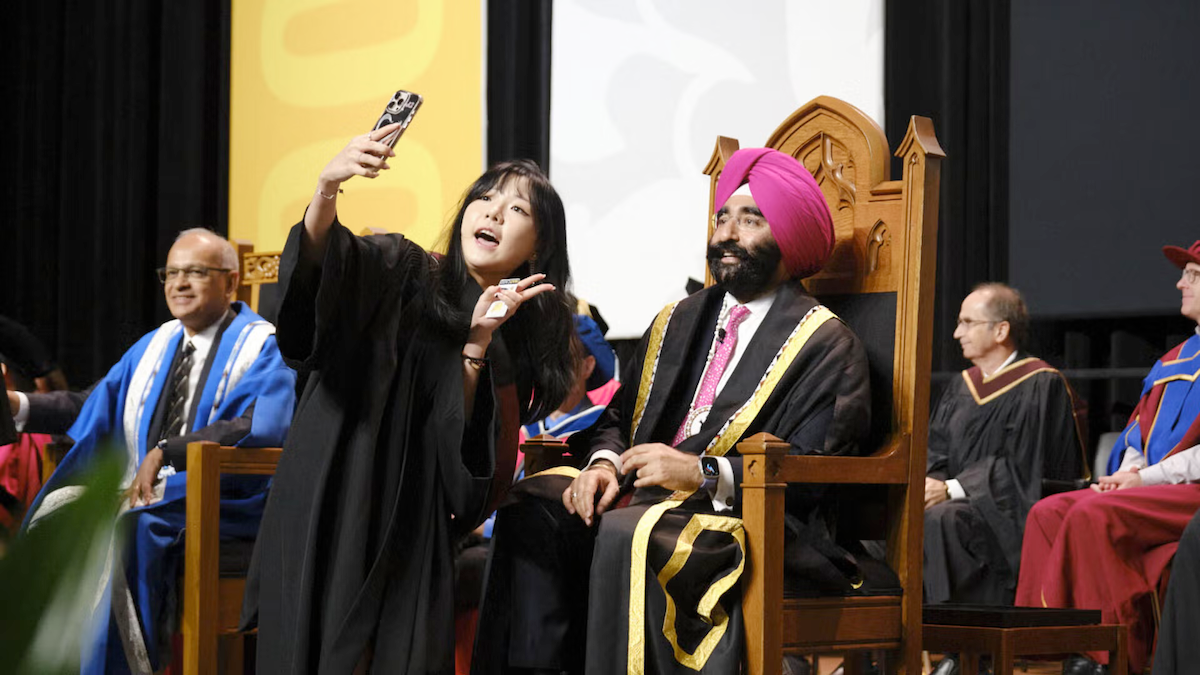 A young woman takes a selfie with Chancellor Jagdeep Singh Bachher at Convocation.