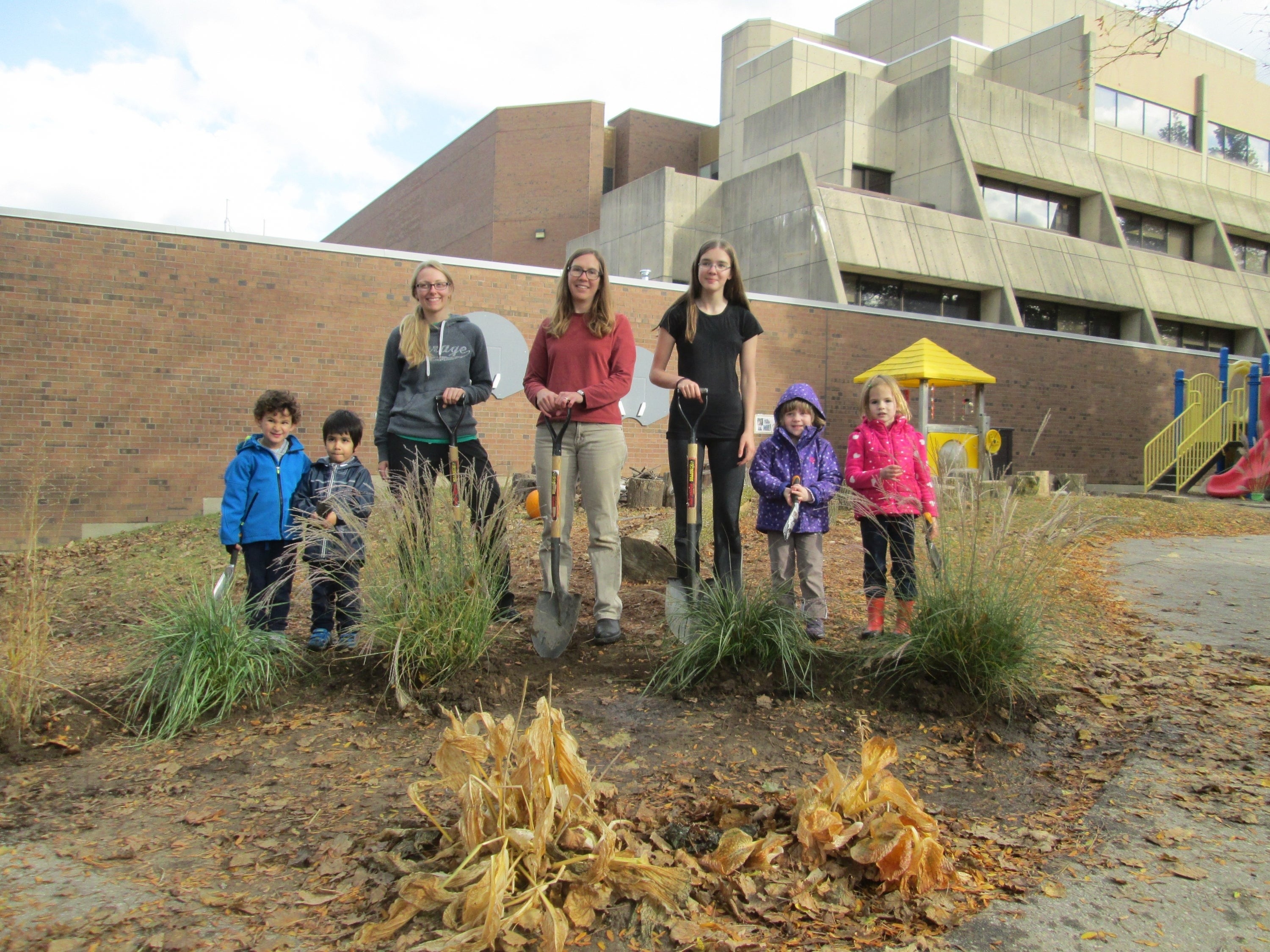 Volunteers and daycare students stand in their garden outside the PAS building.