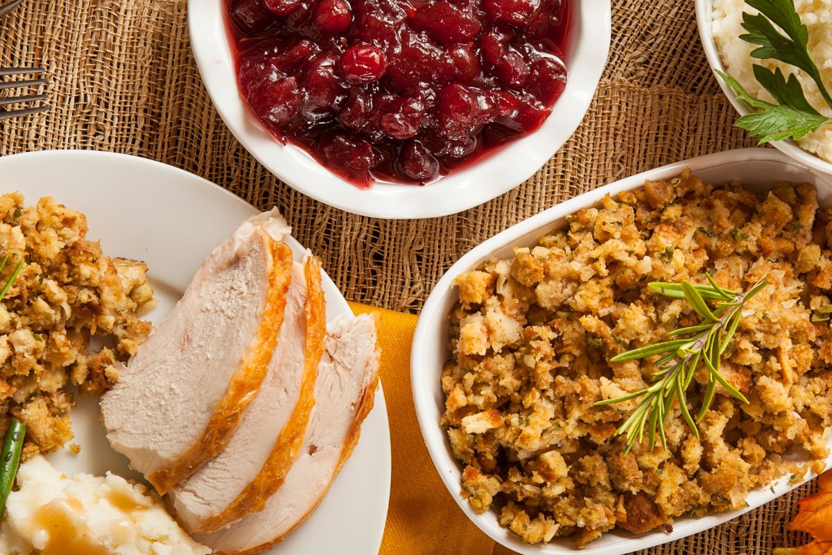 A traditional Christmas dinner featuring separate dishes of roasted turkey, stuffing, mashed potatoes and cranberry sauce