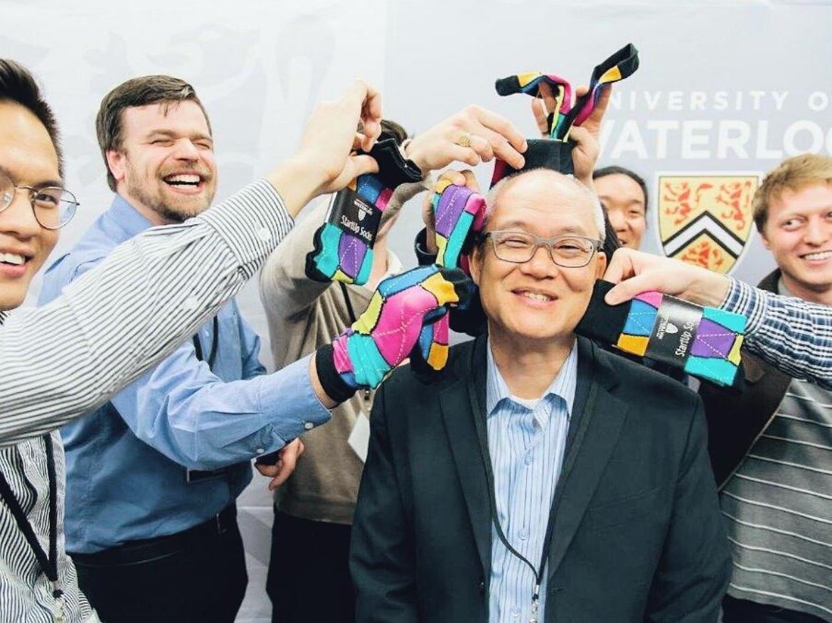 Wayne Change smiles as his students hold up Waterloo-branded socks to his head.