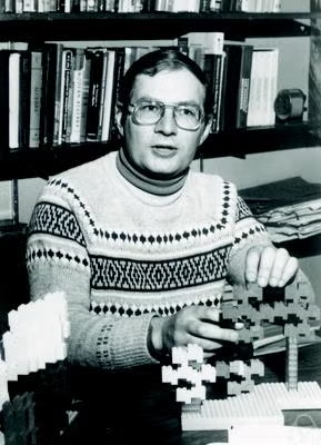 Professor William Gilbert, wearing a sweater, manipulates mathematical models on his desk.