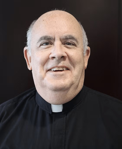 Father Tim Uniac wears a priest's collar and black shirt.