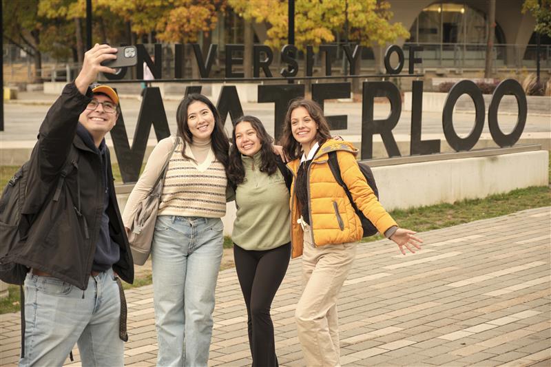Students take a group selfie in front of the Waterloo sign.
