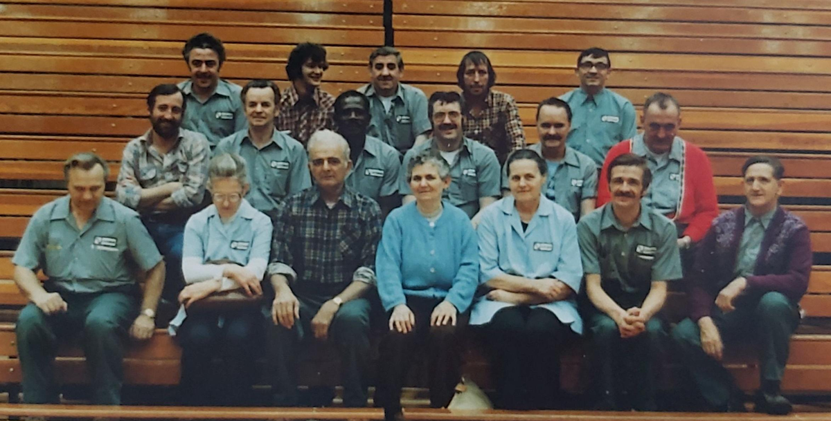 Eugene Kowalski and members of the Custodial section sit on the bleachers in the PAC.