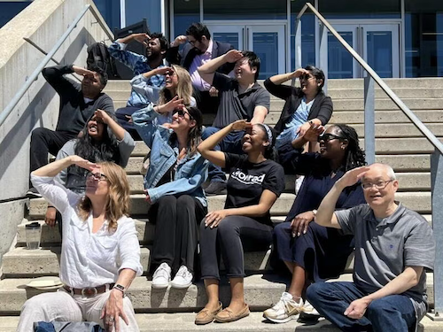 Professor Wayne Chang and several students shield their eyes from the sun.