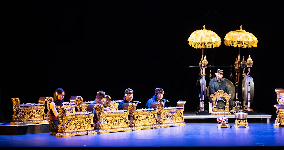 Balinese Gamelan ensemble in traditional regalia performing on stage.