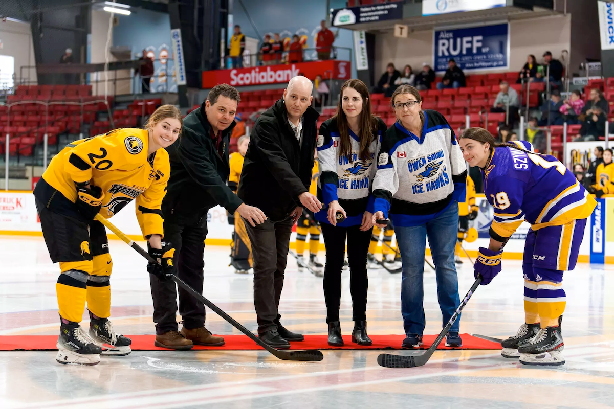 A Waterloo Warriors player and an Owen Sound player at a ceremonial puck drop.