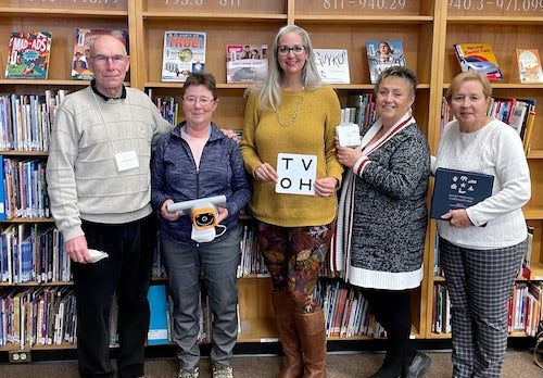 Five members of the screening group stand together in a school library.