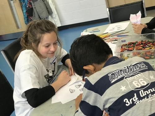 Children using crayons to colour a page.