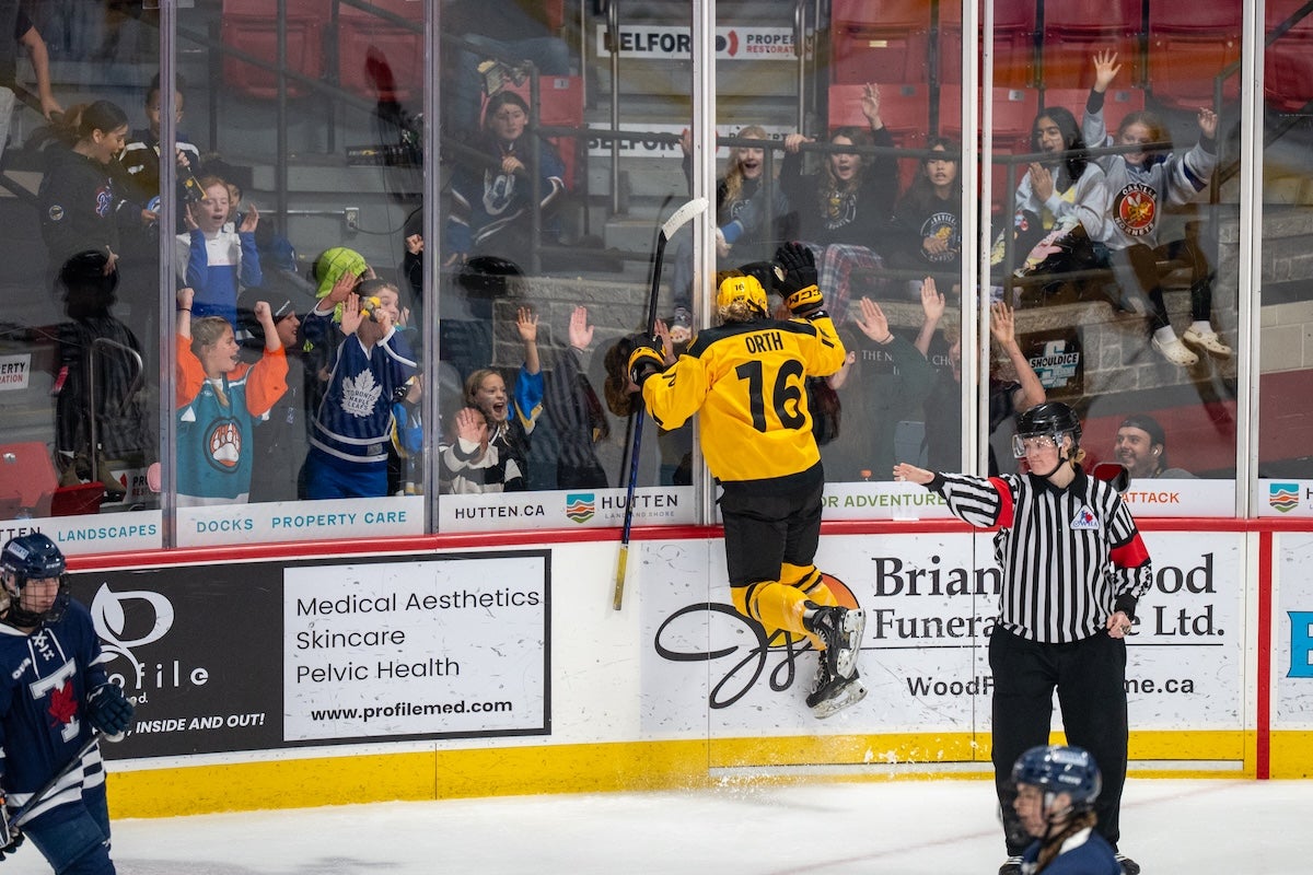 Carly Orth jumps into the boards in celebration after scoring the game-winning goal in overtime.