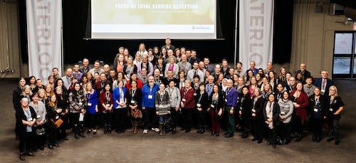 Employees celebrating employment milestones pose for a group photo in Fed Hall.