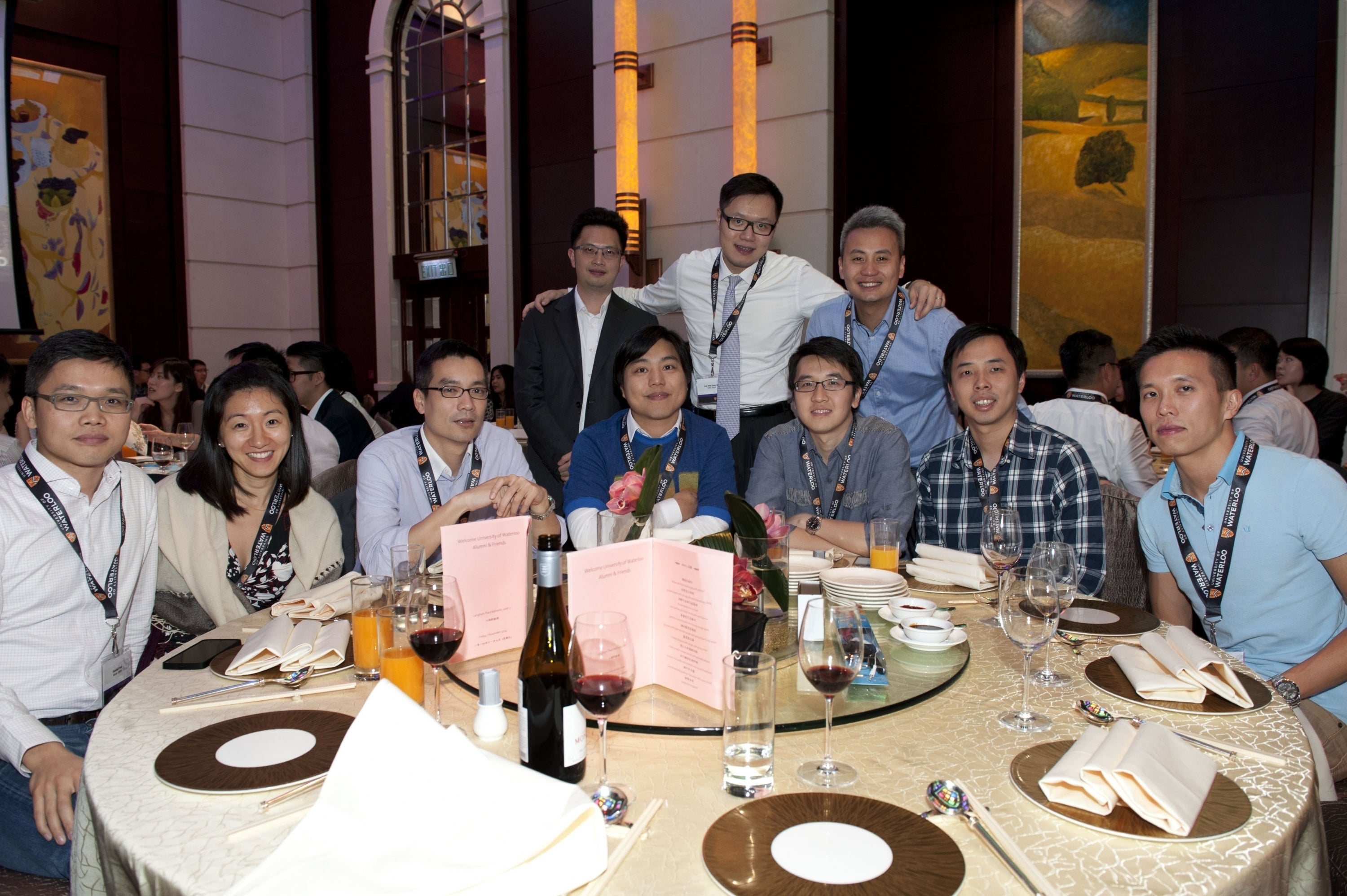 Waterloo alumni pose around a table at an alumni dinner event.