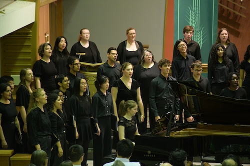 Members of the University Choir sing on stage.
